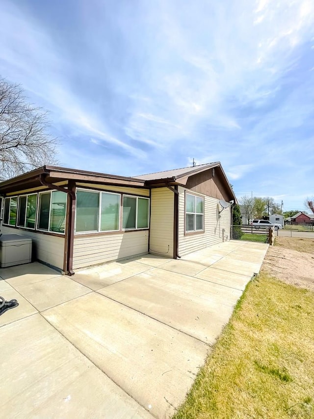 view of front of property with concrete driveway, fence, and a patio area