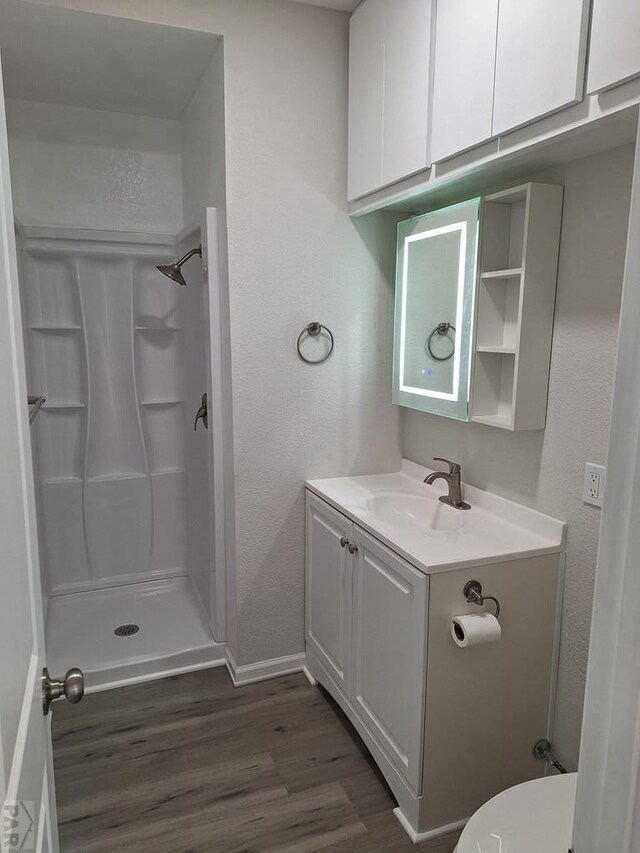 211 W Maplewood, Walsh, CO 81090 - full bathroom featuring a stall shower, wood finished floors, a textured wall, vanity, and baseboards