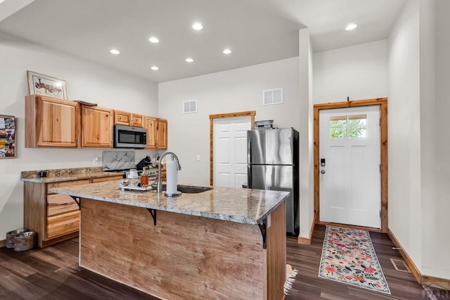 349-351 W Buttercup Way, Pueblo West, CO 81007 - kitchen featuring stainless steel appliances, dark wood finished floors, light stone counters, recessed lighting, and a center island with sink