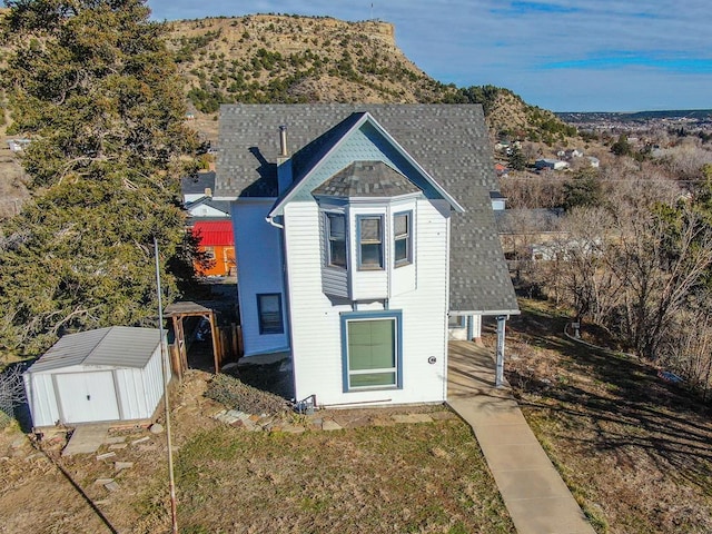 victorian house featuring a shed, roof with shingles, a mountain view, and an outbuilding