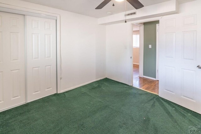 unfurnished bedroom featuring a ceiling fan, visible vents, dark colored carpet, and a closet