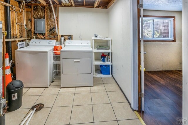 washroom with light tile patterned floors, electric panel, a textured ceiling, and independent washer and dryer