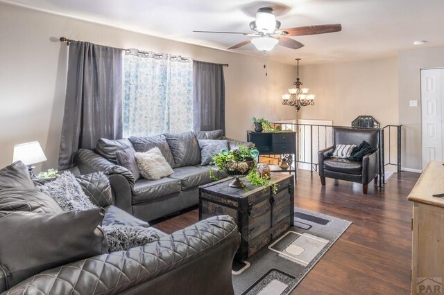 living room featuring dark wood finished floors, baseboards, and ceiling fan with notable chandelier