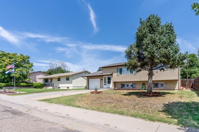 view of front facade with a garage, fence, driveway, stucco siding, and a front yard