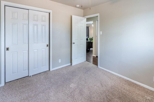 unfurnished bedroom featuring a closet, baseboards, and carpet flooring