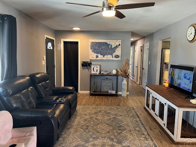 living area featuring ceiling fan, wood finished floors, and baseboards