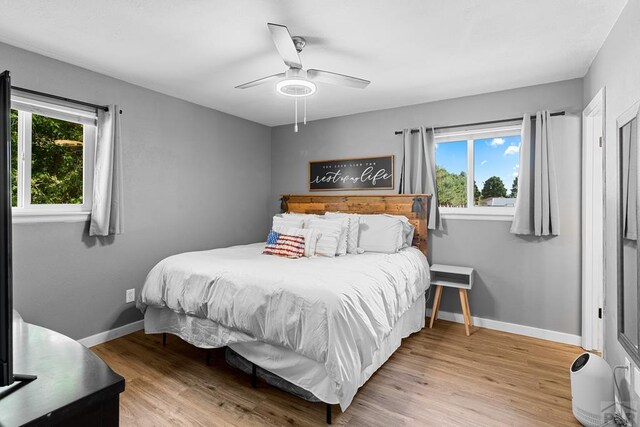 bedroom with light wood-type flooring, a ceiling fan, and baseboards