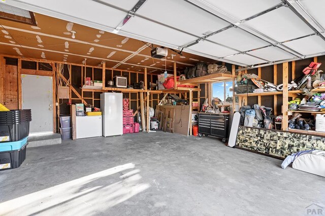 garage with a garage door opener and freestanding refrigerator