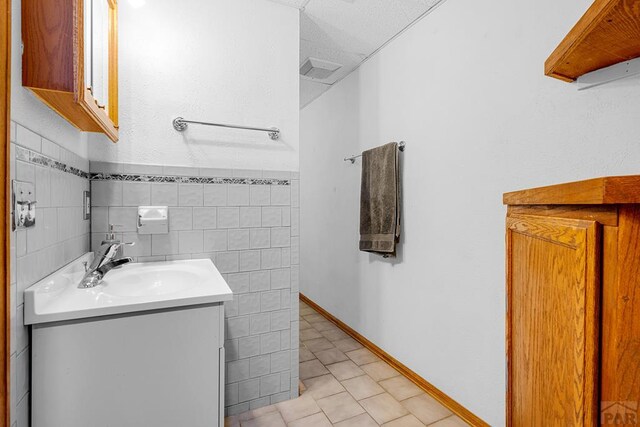 bathroom featuring tile patterned flooring, tile walls, and vanity