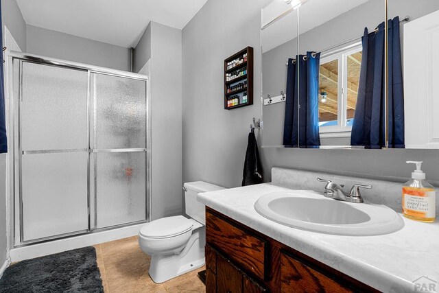 bathroom featuring a stall shower, vanity, toilet, and tile patterned floors