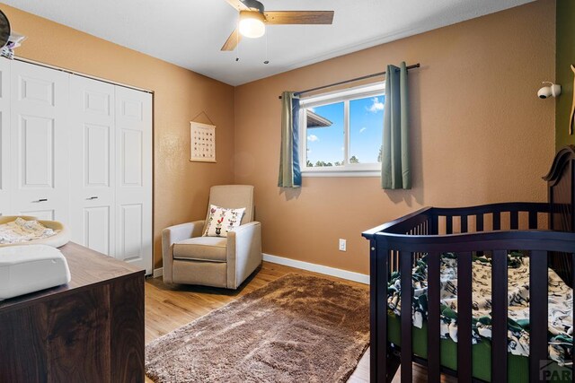 bedroom with a closet, light wood-type flooring, a ceiling fan, and baseboards