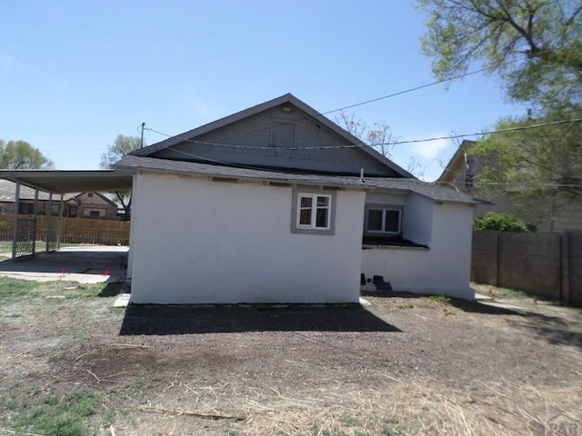 view of property exterior featuring fence, stucco siding, and an attached carport