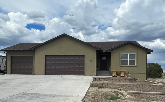 ranch-style house with driveway, an attached garage, and stucco siding