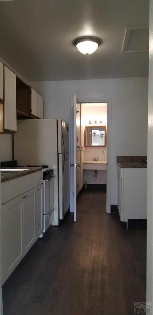 kitchen featuring dark wood-style flooring, dark countertops, a sink, and white cabinets