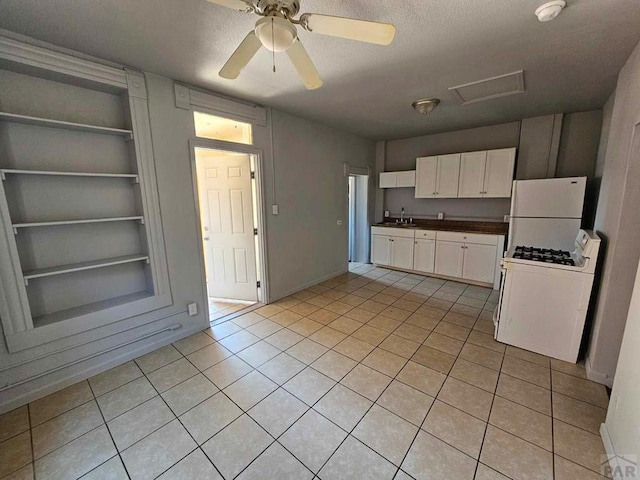 kitchen with built in shelves, white appliances, a sink, white cabinets, and dark countertops