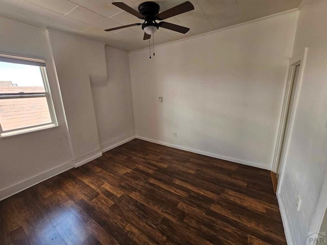 spare room featuring dark wood finished floors, a ceiling fan, and baseboards