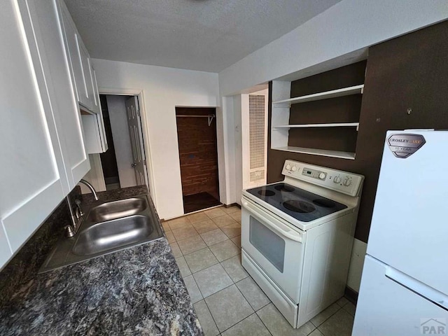 kitchen with light tile patterned floors, a textured ceiling, white appliances, a sink, and open shelves