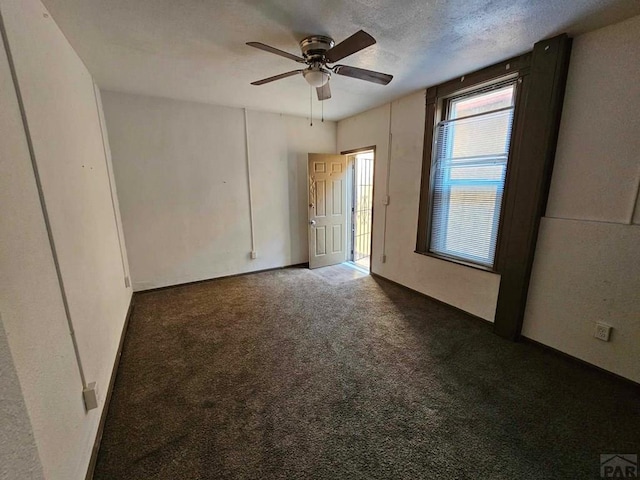 unfurnished bedroom with dark carpet, a textured ceiling, and ceiling fan