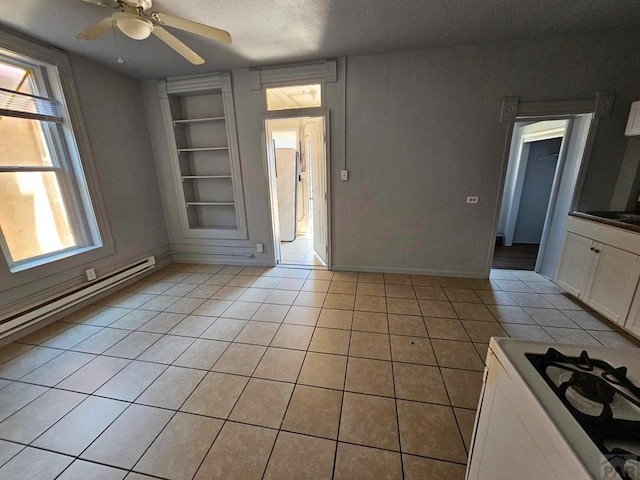 spare room with light tile patterned floors, a ceiling fan, a baseboard radiator, a textured ceiling, and built in shelves