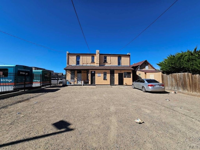 view of front of house with uncovered parking and fence