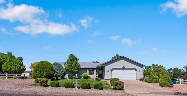 single story home featuring concrete driveway, fence, an attached garage, and stucco siding