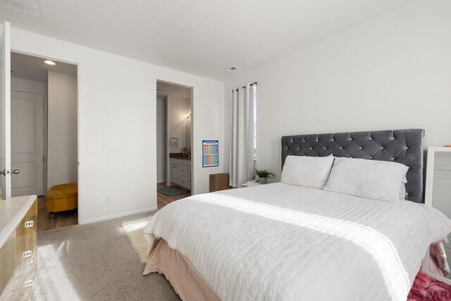 bedroom featuring ensuite bathroom, carpet flooring, and baseboards