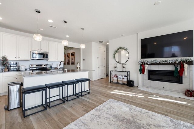 kitchen featuring a breakfast bar area, open floor plan, stainless steel appliances, white cabinetry, and pendant lighting