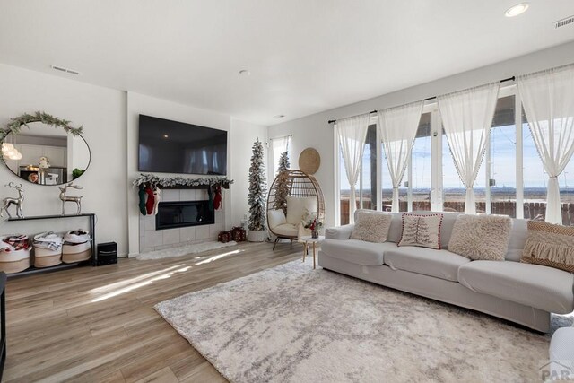 living area featuring a fireplace, wood finished floors, and visible vents