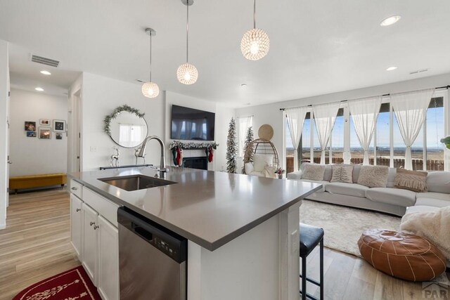 kitchen with a sink, white cabinets, stainless steel dishwasher, and open floor plan