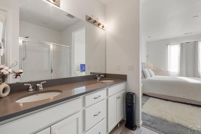 ensuite bathroom featuring a sink, visible vents, a shower stall, double vanity, and ensuite bath