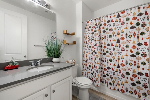 bathroom with visible vents, toilet, shower / tub combo, vanity, and wood finished floors