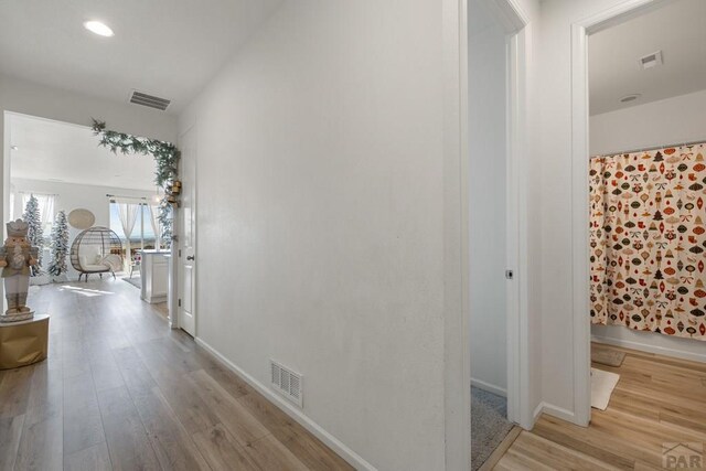 hall featuring light wood-style floors, baseboards, visible vents, and recessed lighting