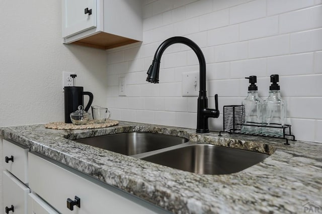 1709 Henry Ave, Pueblo, CO 81005 - kitchen view of a sink, decorative backsplash, light stone countertops, and white cabinets