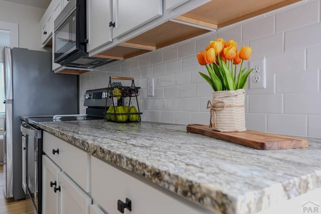 1709 Henry Ave, Pueblo, CO 81005 - kitchen featuring stainless steel range with electric stovetop, black microwave, white cabinets, and decorative backsplash