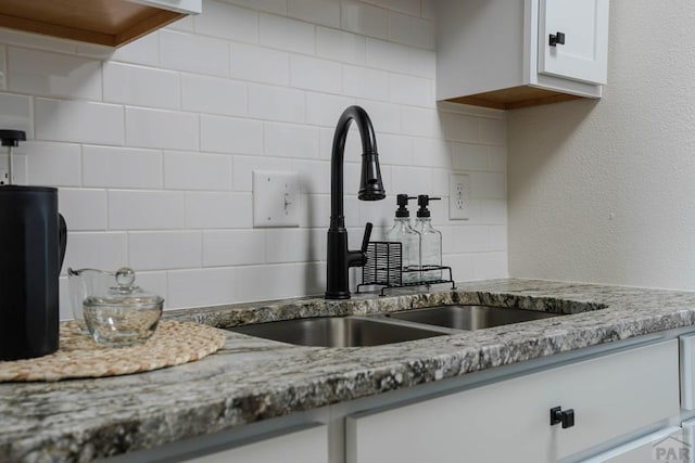 1709 Henry Ave, Pueblo, CO 81005 - kitchen featuring a sink, decorative backsplash, white cabinets, and light stone countertops