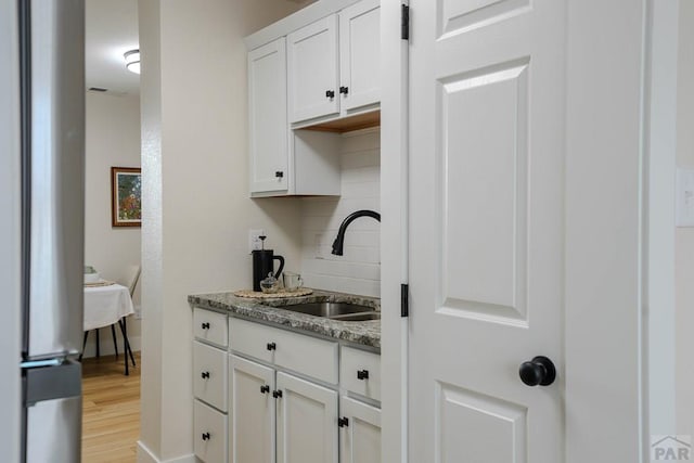 1709 Henry Ave, Pueblo, CO 81005 - bar with a sink, light wood finished floors, baseboards, and decorative backsplash