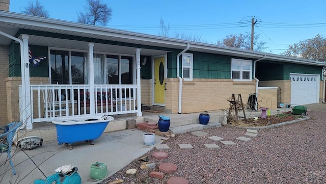 single story home featuring an attached garage, a porch, and brick siding