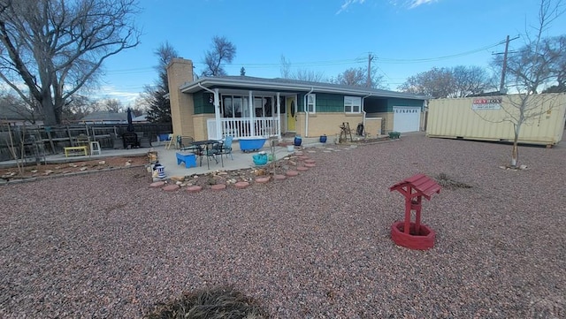 view of front of property featuring a garage, a patio, a chimney, and fence