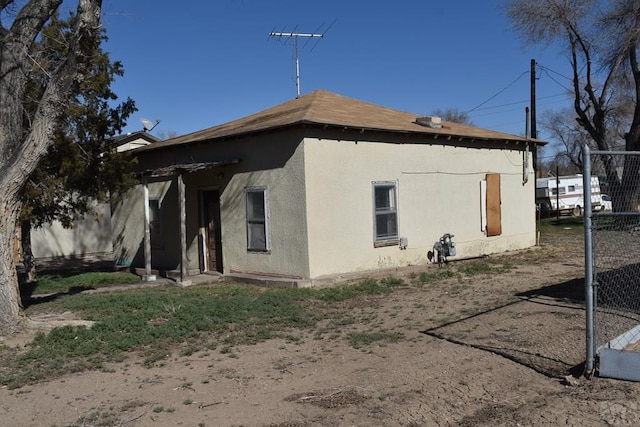 view of property exterior with stucco siding and fence