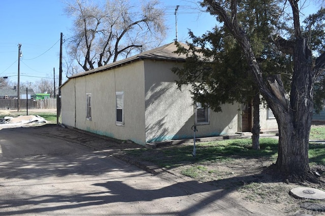 view of home's exterior with stucco siding and fence