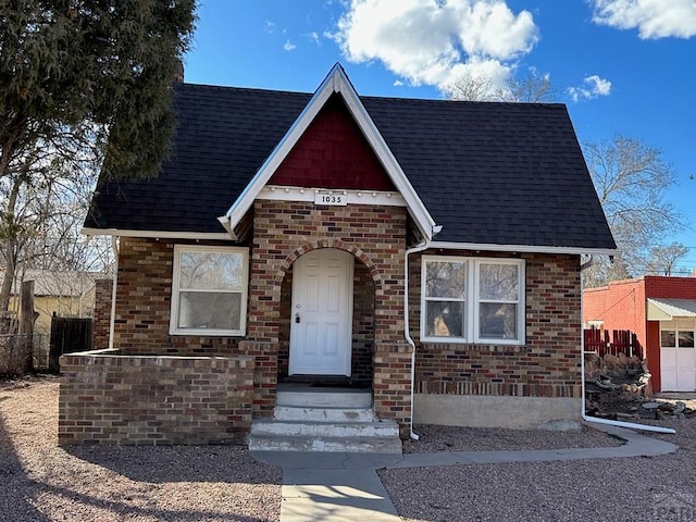 view of front of house featuring brick siding and roof with shingles