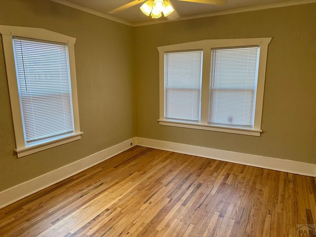 empty room featuring baseboards, wood finished floors, a ceiling fan, and crown molding