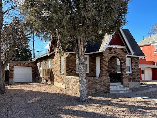 view of front facade featuring a shingled roof, an outbuilding, gravel driveway, and brick siding