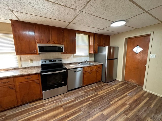 kitchen featuring dark wood-style floors, appliances with stainless steel finishes, a sink, and tasteful backsplash