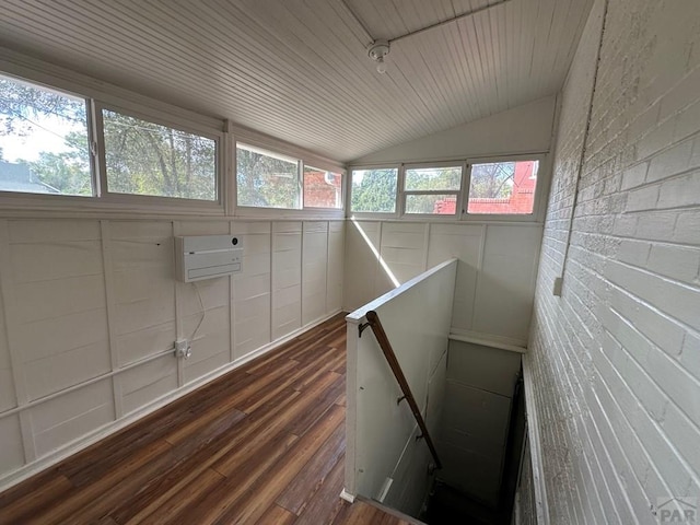 interior space featuring lofted ceiling, brick wall, wood ceiling, wood finished floors, and a wall mounted air conditioner