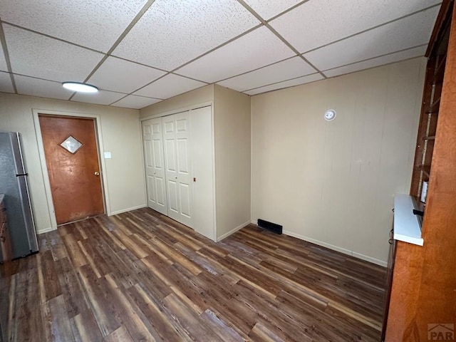 foyer featuring a paneled ceiling, baseboards, and dark wood-style flooring