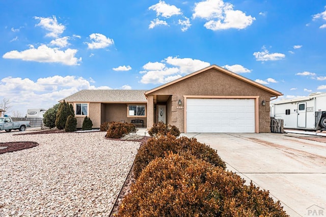 ranch-style house featuring a garage, driveway, and stucco siding