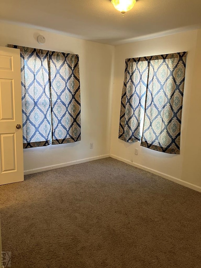 empty room featuring carpet and baseboards