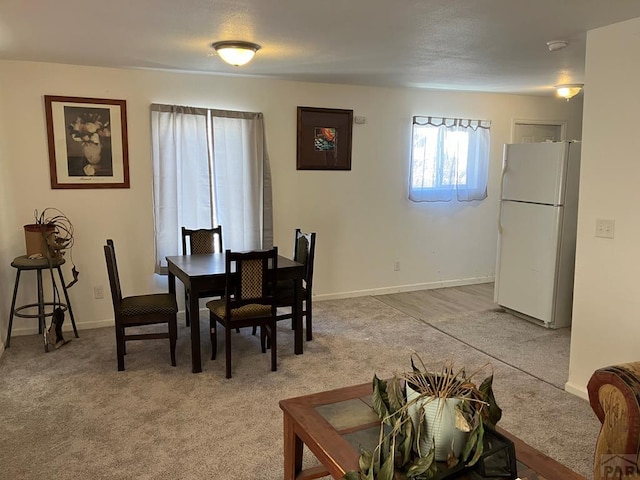 dining space featuring light colored carpet and baseboards