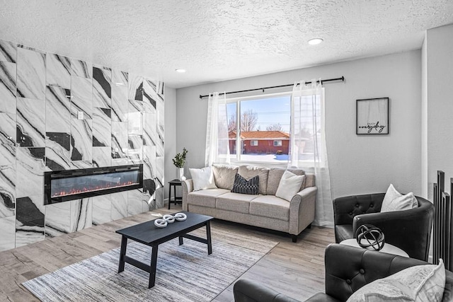 living area featuring a textured ceiling, light wood finished floors, and a high end fireplace